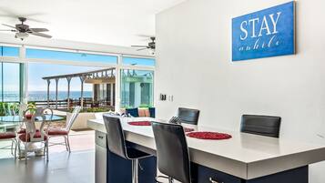 A modern kitchen with a large island, white cabinets, and a view of the outdoors.