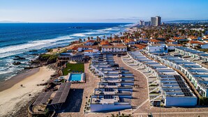 Ein Küstenhotel mit mehreren Gebäuden, einem Strand und einem Steg.