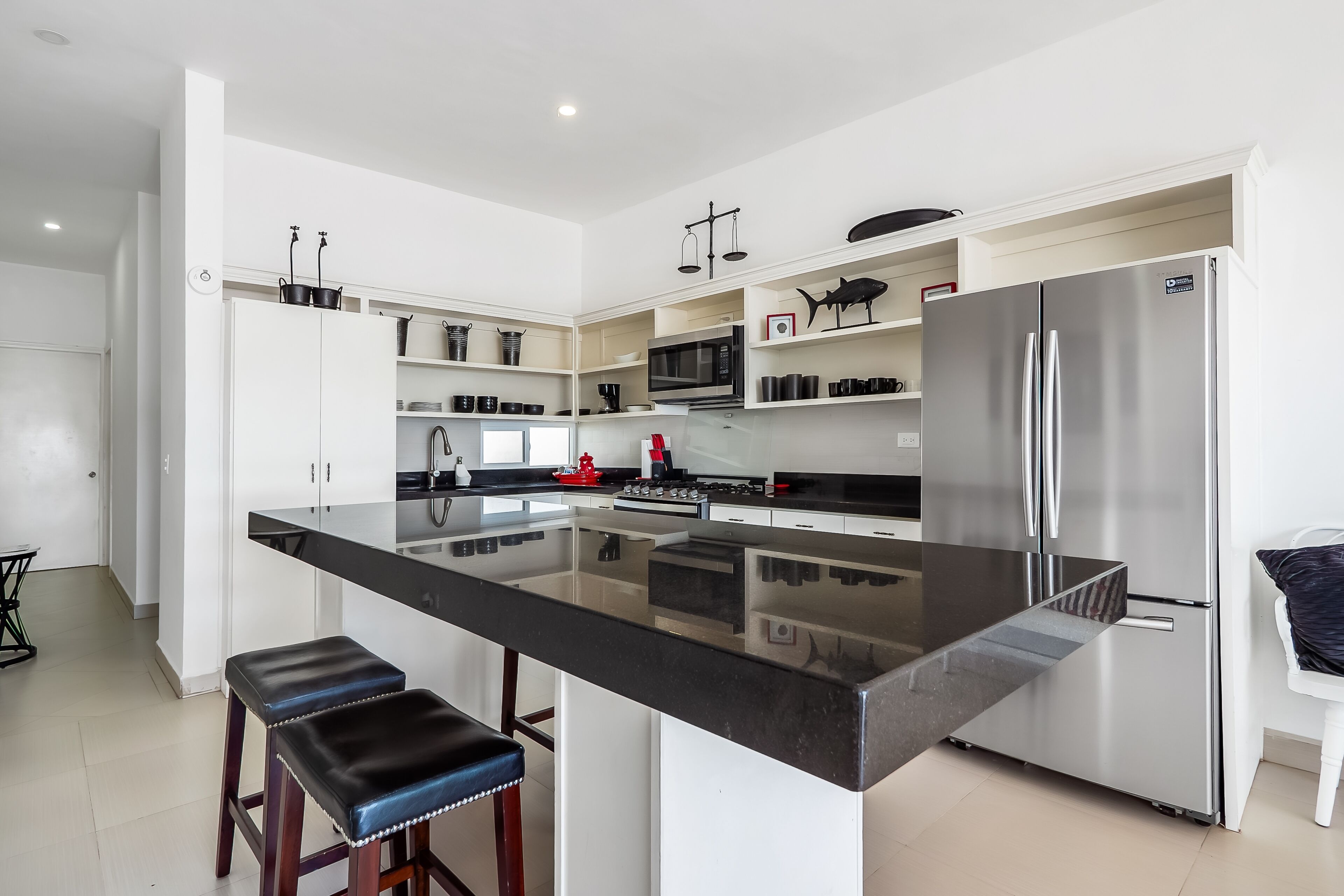 A modern kitchen with a central island, stainless steel appliances, and white cabinetry.