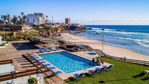 A pool area with blue lounge chairs, a small pool, and a beach view. - 2-story dog-friendly villa with outdoor pool, patio, 2 balconies, streaming, AC (Rosarito)