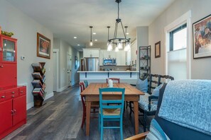 Una cocina moderna con armarios blancos, una mesa de comedor de madera y un mueble rojo.