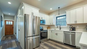 Una cocina moderna con electrodomésticos de acero inoxidable, armarios blancos y salpicadero con diseño.