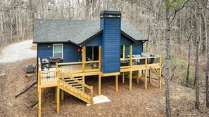 A blue cabin with a deck and stairs, surrounded by trees. - Harris Creek Haven by Mountain Oasis | Secluded North Georgia Mountain Getaway (Ellijay)