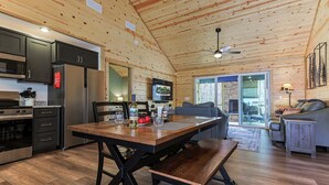 A wooden cabin interior with a kitchen, dining area, and living space.