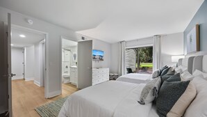 Een slaapkamer met twee bedden, een televisie, een badkamer en uitzicht op de omgeving.