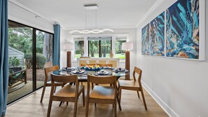 Een eethoek met een glazen tafel, houten stoelen en uitzicht op de omgeving.