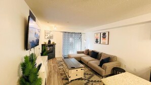 Un salon moderne comprenant un canapé, une table basse, un téléviseur et des objets de décoration.