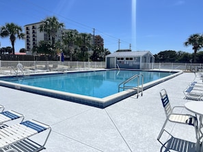 A swimming pool with a tiled deck, lounge chairs, and a small building in the background. - A 11 Sundown Condominiums (Pensacola)