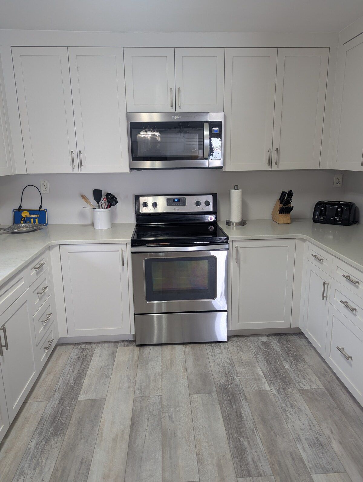 A kitchen with white cabinets, a microwave, a stove, and a toaster.
