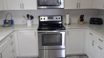 A kitchen with white cabinets, a microwave, a stove, and a toaster.