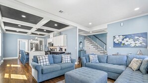 Una sala moderna con un sofá modular, un reposapiés y una escalera que sube al piso superior.