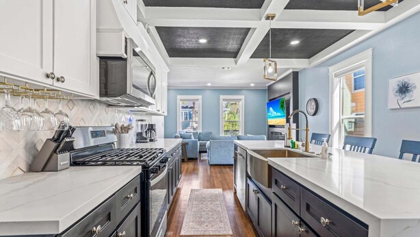 Una cocina moderna con una isla central, un comedor con un sofá azul y vistas al exterior.