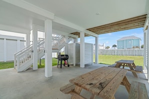Portico coperto con tavolo in legno e barbecue.