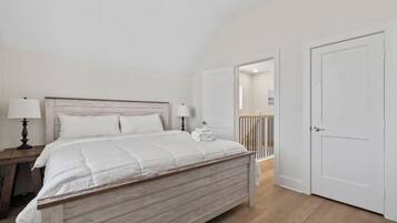Une chambre à coucher avec un lit en bois, une table de chevet, une lampe et une porte donnant sur une autre pièce.