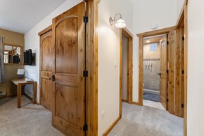 A hallway with wooden doors, a small table with a lamp, and a shower area with tiled walls. - Vail Townhome | Hot Tub, Trails, Fireplace (Vail)
