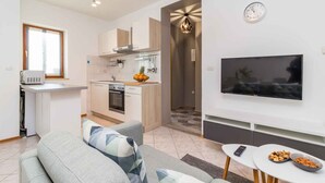 A modern apartment with a kitchen, living area, and a TV. - Holiday apartment with swimming pool, playground and barbecue (Valbandon)