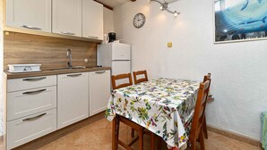 Cozinha com armários brancos, pia, cafeteira e relógio na parede.