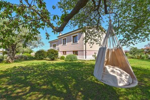 Ein Haus mit einer Hängematte in einem Garten.