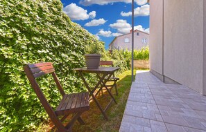 A wooden bench and table set against a hedge, with a paved pathway and a building in the background. - Holiday apartment tastefully furnished with air conditioning (Pula)