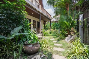 A lush garden with a pathway leading to a building with a balcony. - Chongko 4 Bed Villa, Few Minutes To Rawai (Rawai)