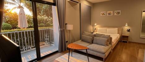 A modern bedroom with a balcony, a sofa, a small table, and a bed.