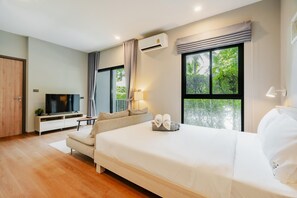 Habitación de hotel con cama, televisión, escritorio y ventana con vista a zonas verdes.