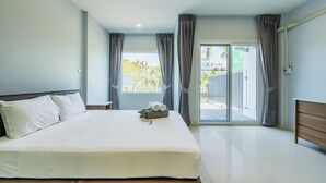 Ein Schlafzimmer mit einem Bett, einem Nachttisch, einem Fenster mit Vorhängen und Blick ins Freie.