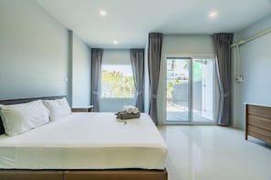 A bedroom with a bed, a nightstand, a window with curtains, and a view of the outside. - Boathouse 4 Bed Townhouse Fully Renovated Rawai (Rawai)