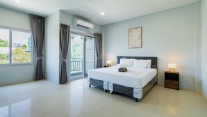 Ein modernes Hotelzimmer mit einem großen Bett, einer Schiebetür zu einem Balkon, einem Deckenventilator und einer Wand-Klimaanlage.
