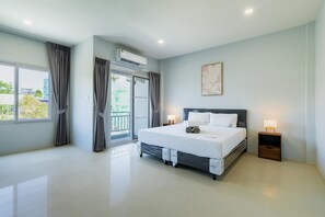 A modern hotel room with a large bed, a sliding door to a balcony, a ceiling fan, and a wall-mounted air conditioner. - Boathouse 4 Bed Townhouse Fully Renovated Rawai (Rawai)