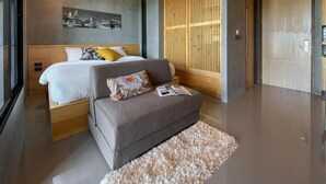 Quarto moderno com cama, sofá, divisória de madeira e uma obra de arte com vista para a cidade na parede.