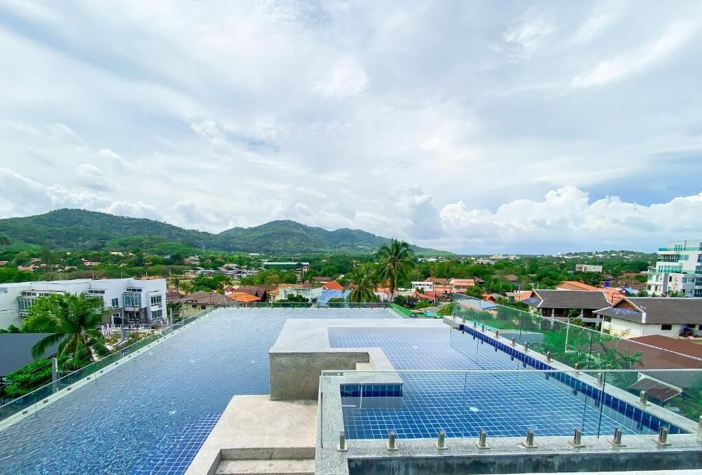 Ein Infinity-Pool auf dem Dach mit Blick auf eine Stadt und Berge.