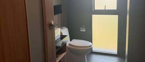A bathroom with a toilet, a sink, and a window.