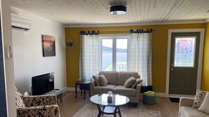 Un salon avec un canapé, une table basse, un téléviseur et une fenêtre avec des rideaux.