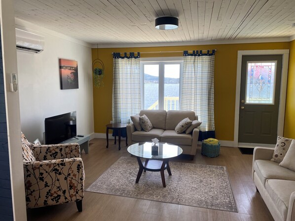 A living room with a sofa, a coffee table, a TV, and a window with curtains.