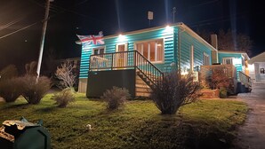 Une petite maison de plain-pied avec un porche, un drapeau et une cour avant bien éclairée.