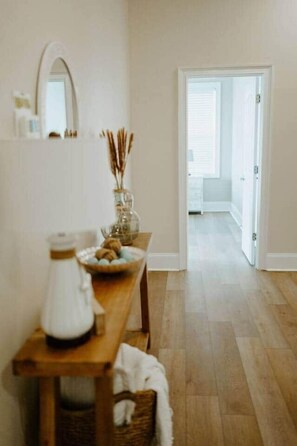 Ein Zimmer mit einer hölzernen Bank, einer weißen Vase und einem Spiegel an der Wand.
