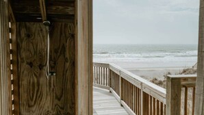 En træterrasse der fører ned til en strand med udsigt over havet.