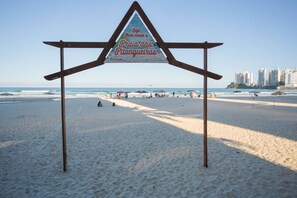 Ein Strandschild mit einer dreieckigen Struktur und einer Beschriftung auf Portugiesisch.