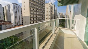 A high-rise residential building with multiple balconies, a glass railing, and a view of other buildings. - Apto com Churrasqueira e Vaga a 200m da Praia (Guarujá)