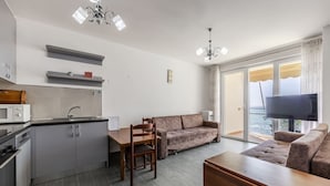 A modern kitchen with a dining area, a sofa, and a TV. - Beachfront Apartment With Pool Access (Shengjin)