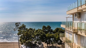 A coastal building with a balcony overlooking the sea, trees in the foreground, and a clear sky. - Beachfront Apartment With Pool Access (Shengjin)
