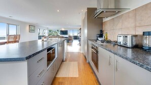 A modern kitchen with a central island, stainless steel appliances, and a view to the outside.