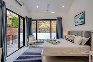 A bedroom with a bed, a chair, a window, and a ceiling fan. - Casa Solana 4bhk Villa w Private Pool nr Candolim (Candolim)