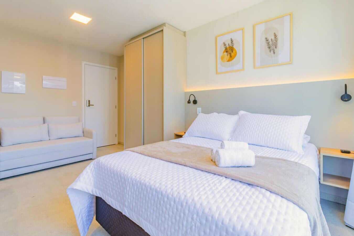 Une chambre à coucher comprenant un lit, des tables de chevet, une commode, un canapé et une armoire.