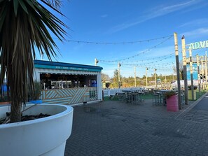 Un restaurante con terraza, un letrero y una maceta grande.