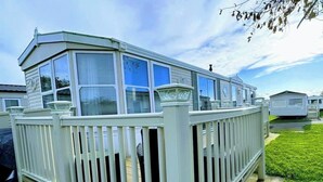 A mobile home with a white exterior, a balcony, and a fenced deck. - Sea Breeze-A Beautiful 3 Bed,Pet Friendly Retreat (Mablethorpe)