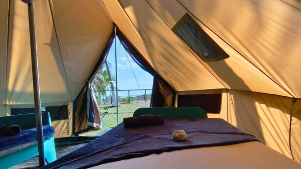 Una tenda amb un llit, una finestra i vista a l'exterior.