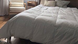 Een slaapkamer met een groot bed, een stoel, een nachtkastje met lamp en een foto aan de wand.