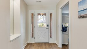 Un couloir avec une porte blanche, un plancher en bois et un tableau accroché au mur.